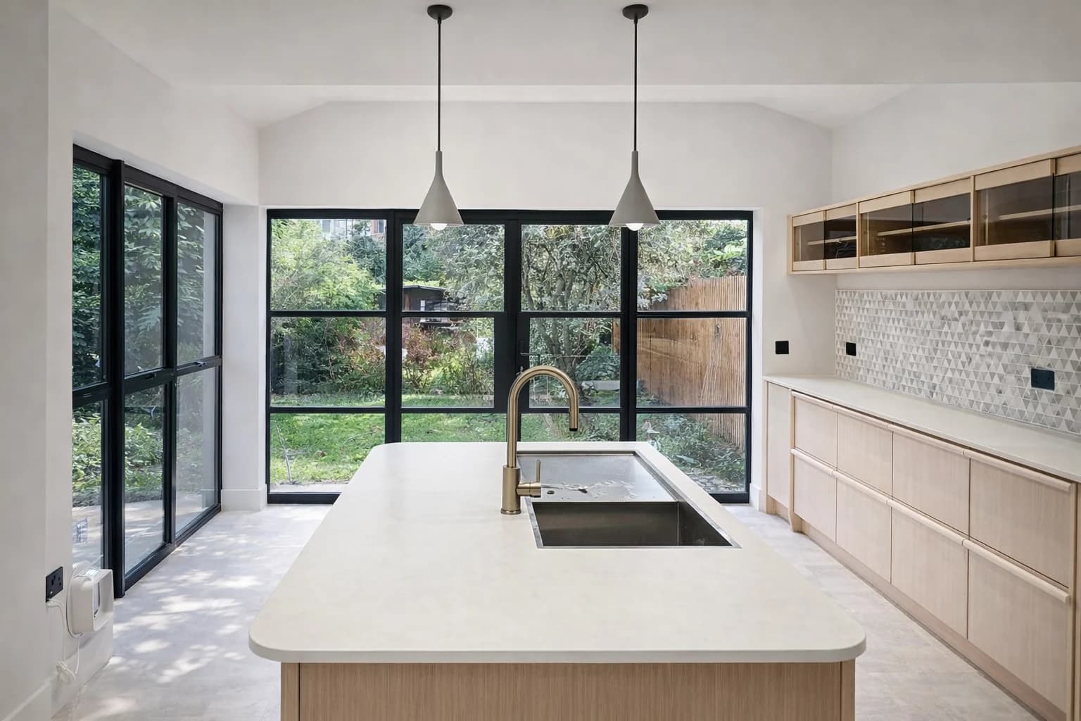 Kitchen island facing black-framed garden glazing