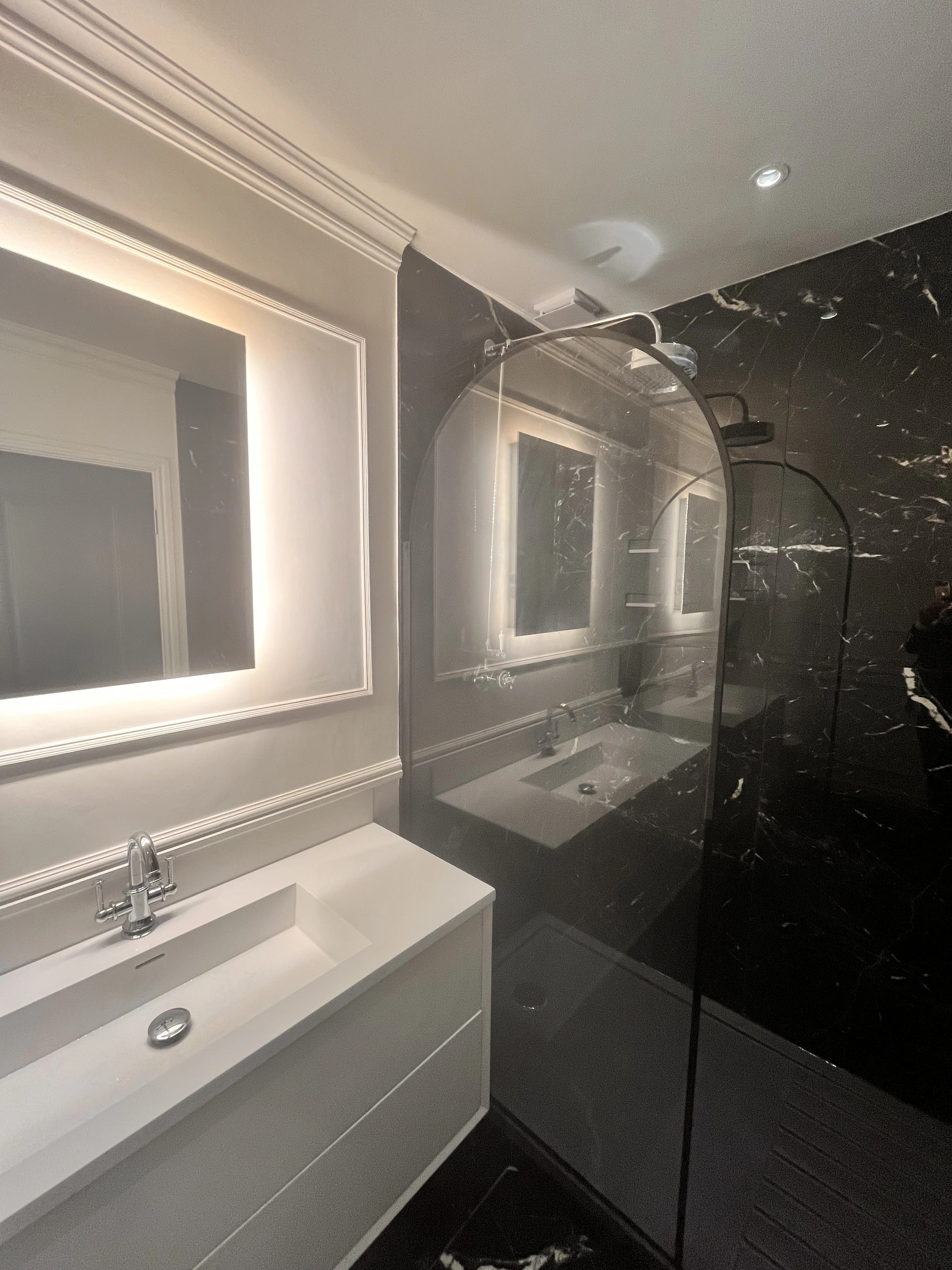 Bathroom with dark shower tiles and a glass shower screen