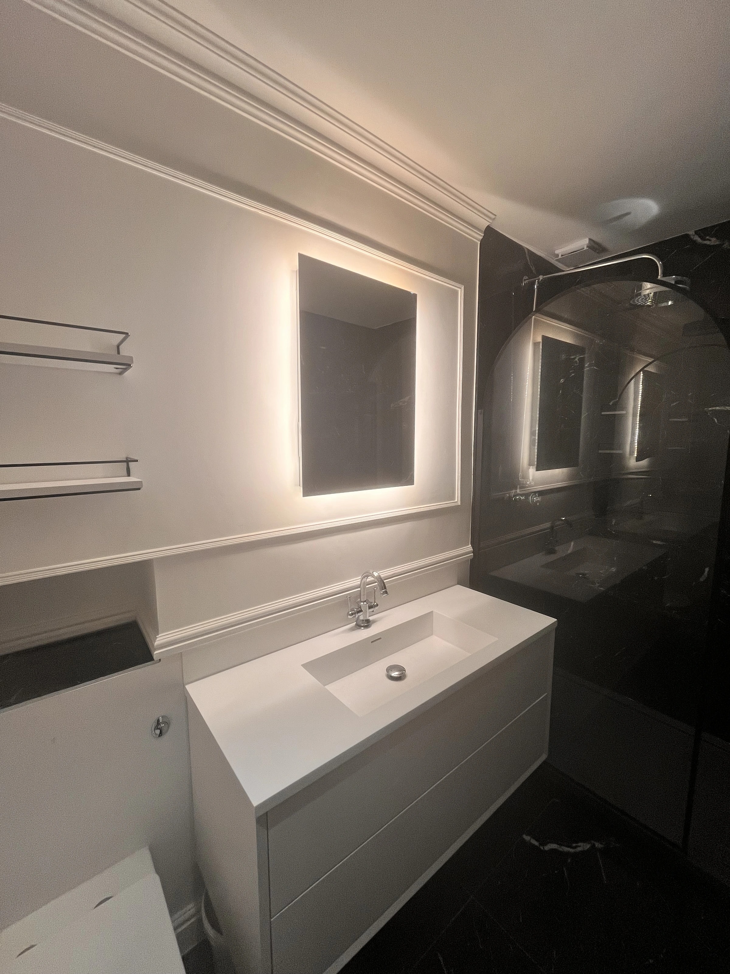 Bathroom vanity and illuminated mirror beside the tiled shower