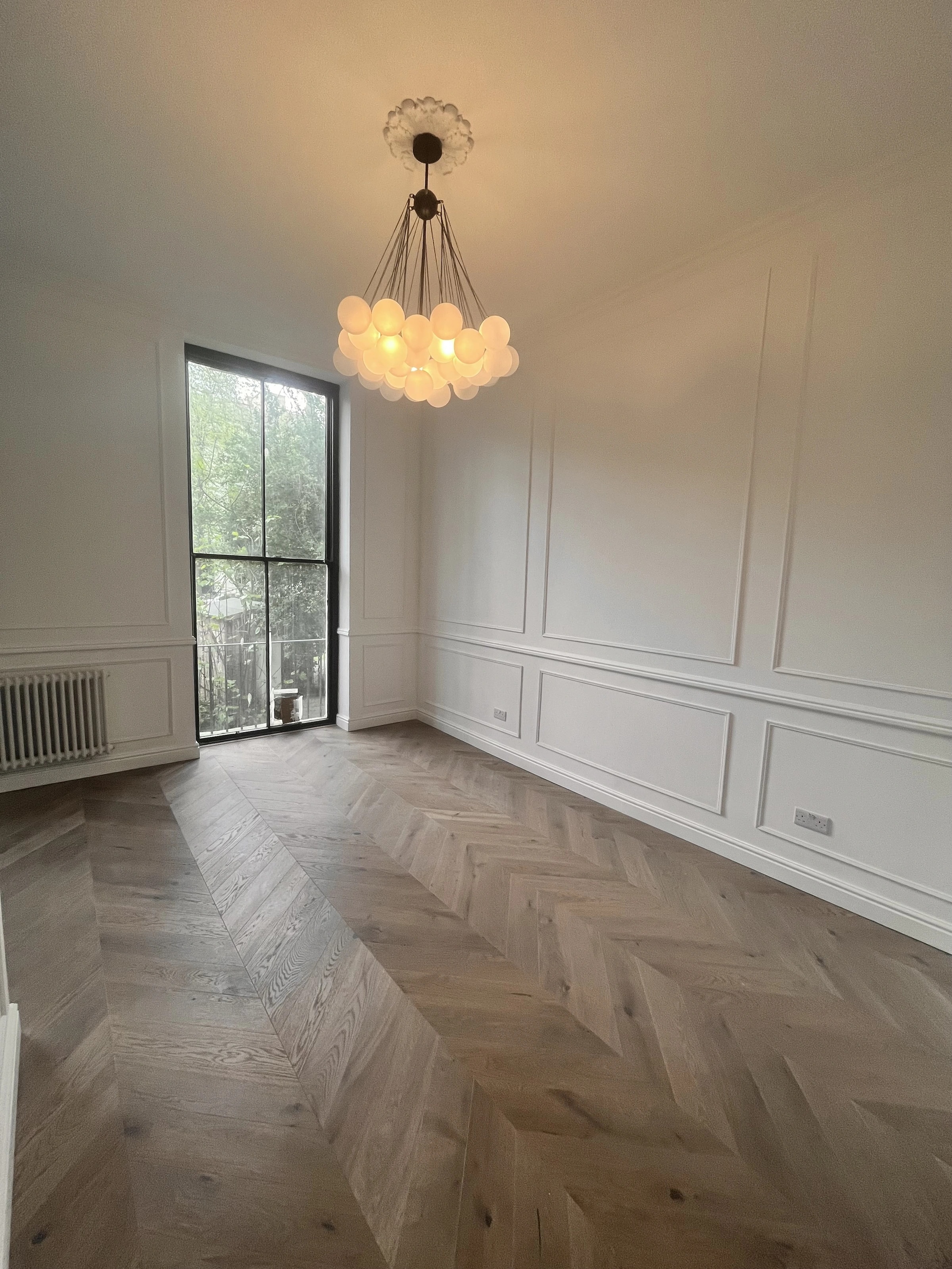 Panelled living room with herringbone floor and pendant lighting