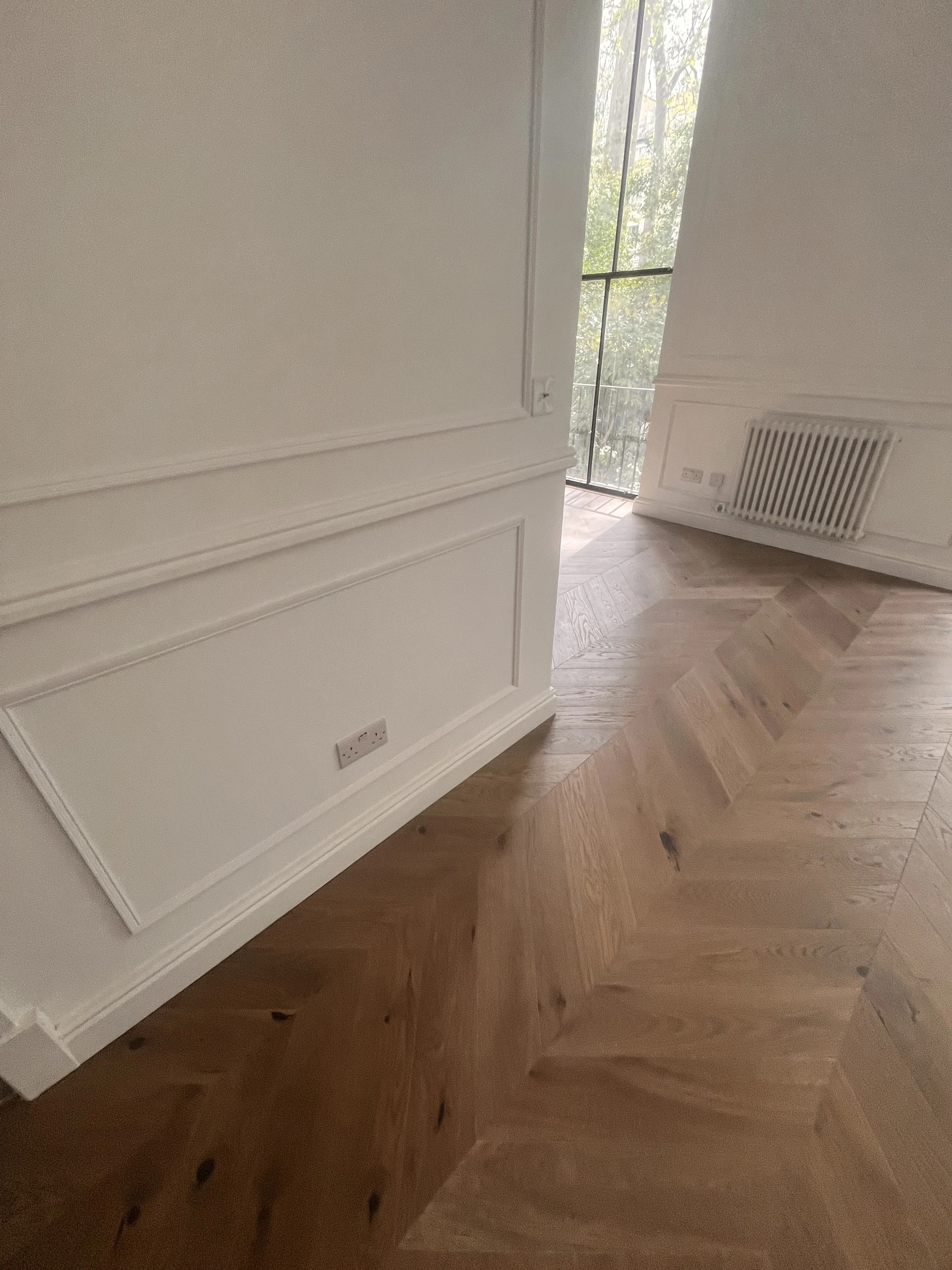 White wall panelling and herringbone flooring in the W2 flat