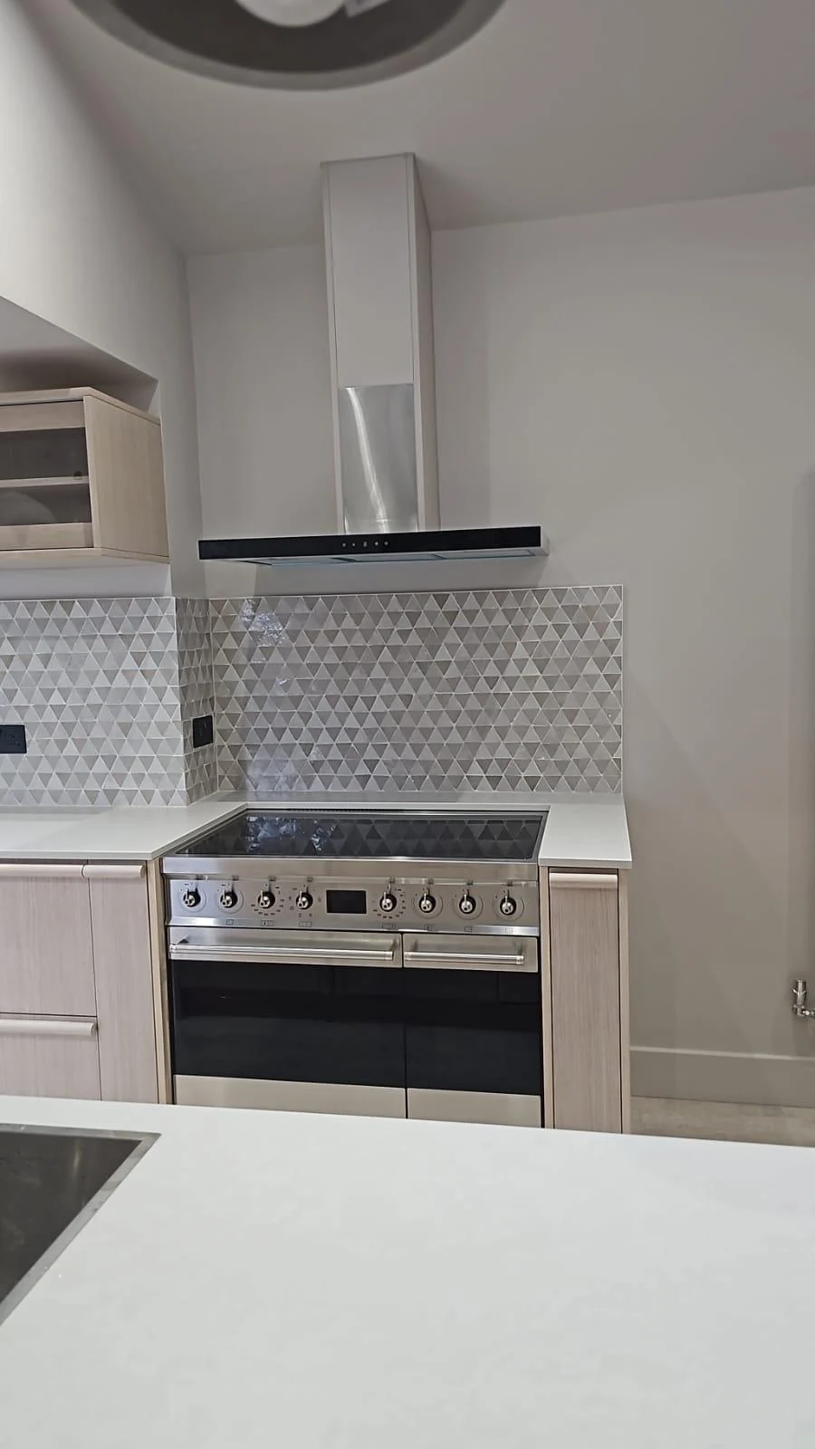 Range cooker beneath a tiled splashback and extractor