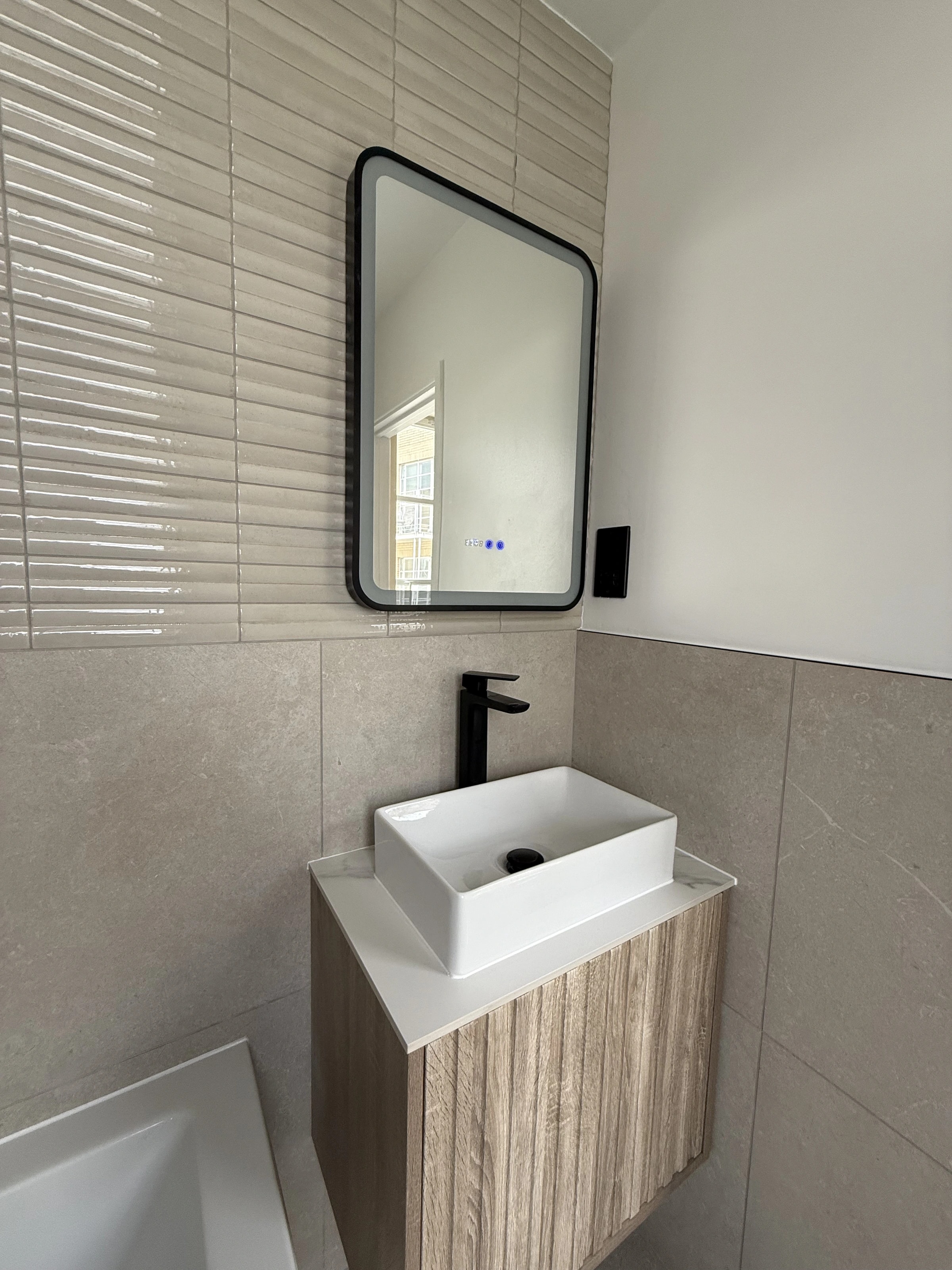Timber bathroom vanity beneath a black-framed mirror