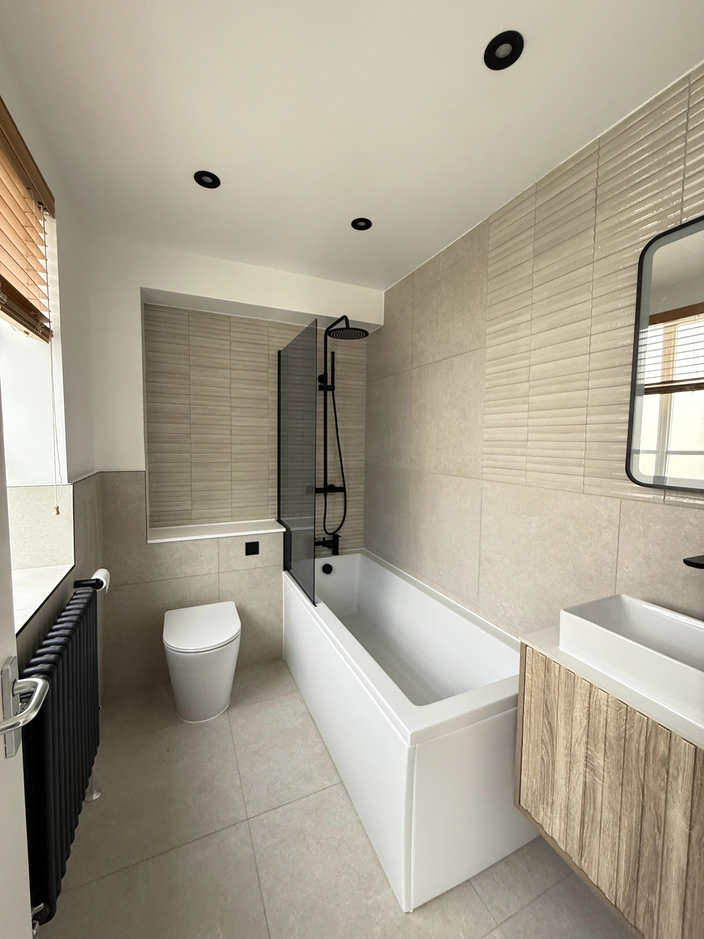 First renovated bathroom with a bath, timber vanity and black fittings