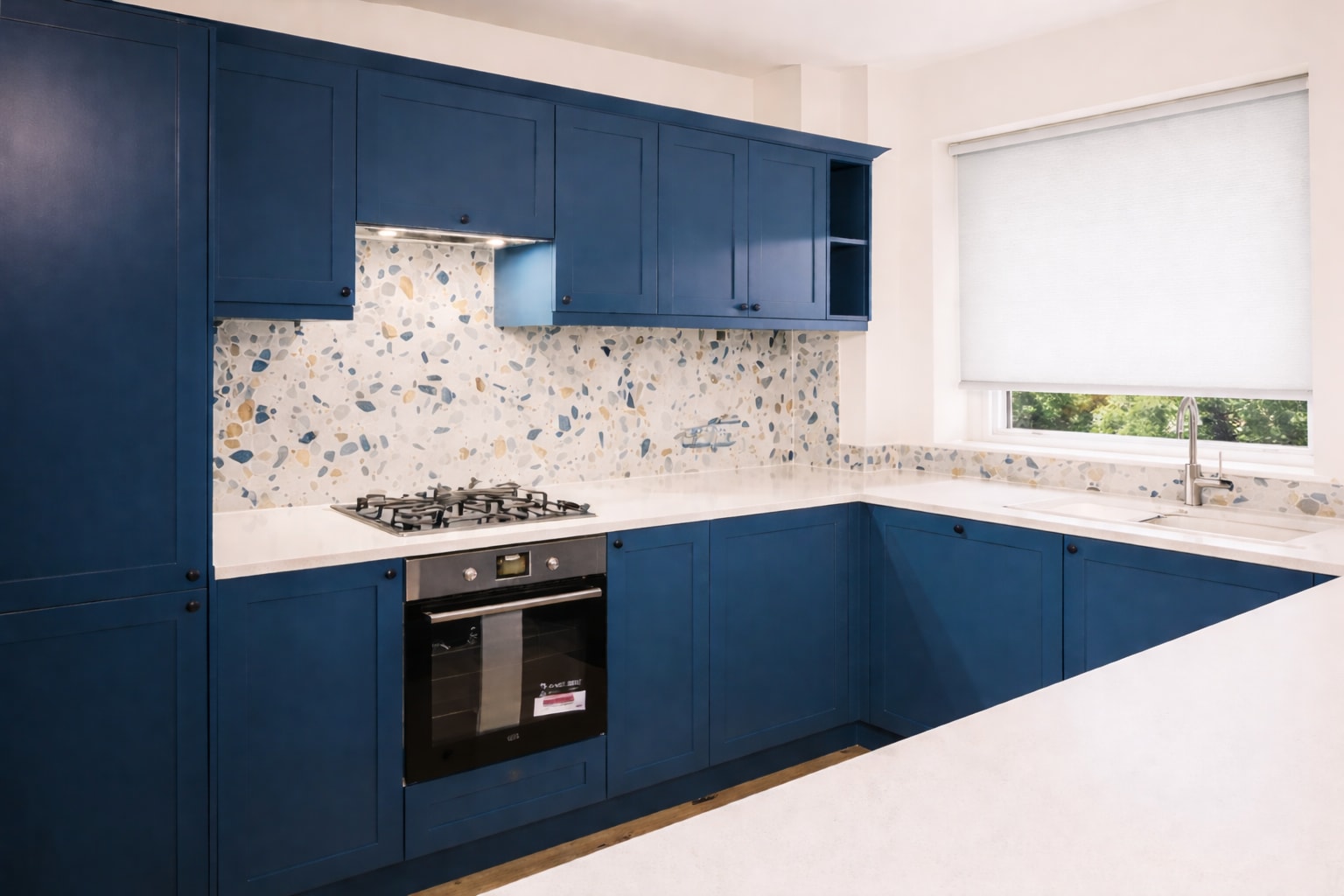 Blue cabinets with a patterned splashback and pale worktop