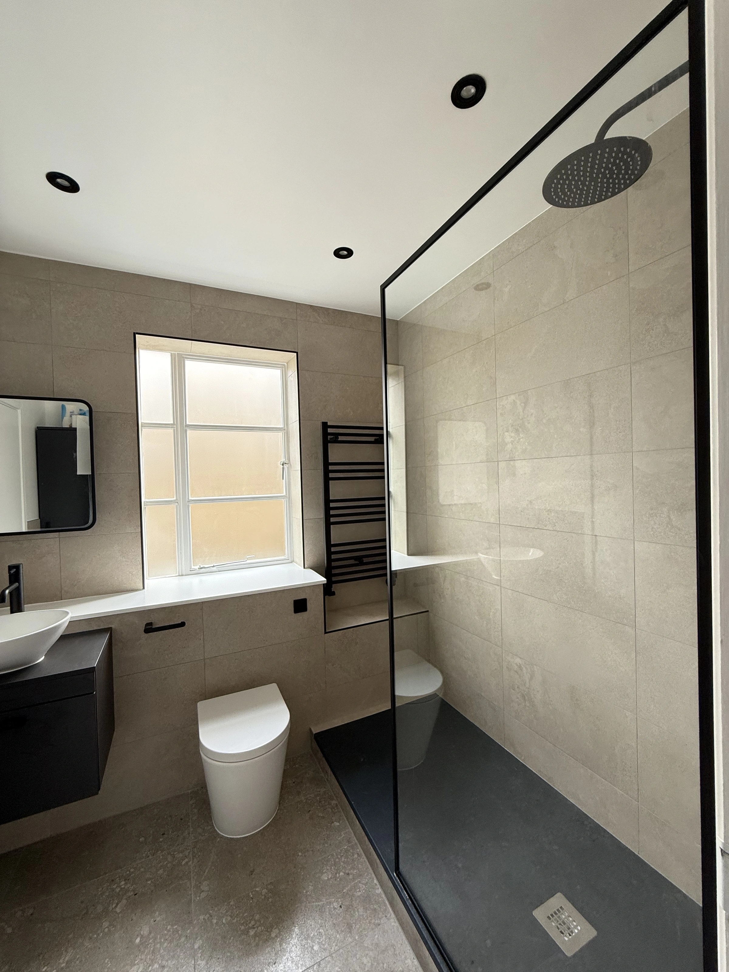 Second renovated bathroom with a walk-in shower and dark vanity