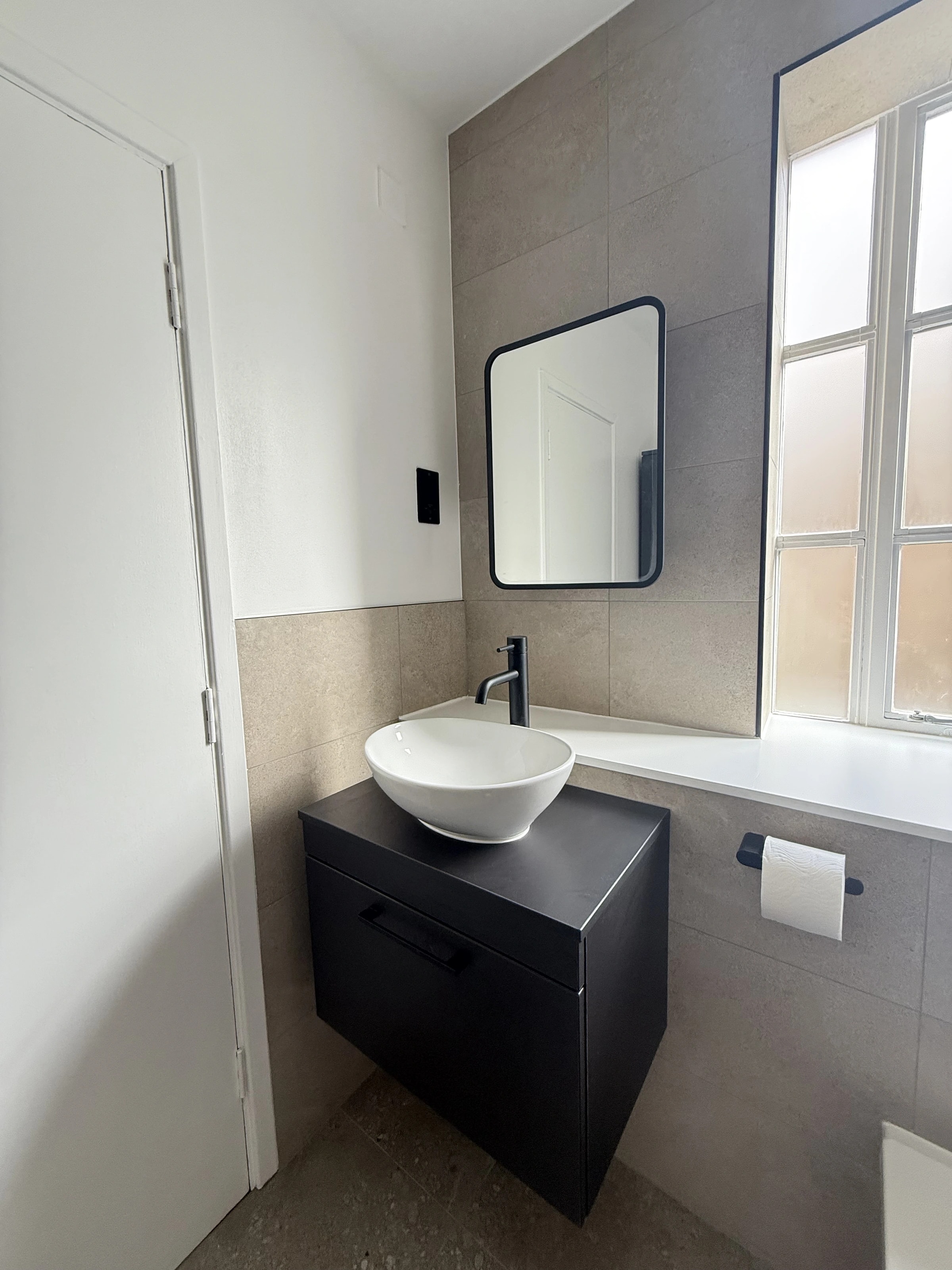 Second bathroom basin and dark vanity beneath the mirror
