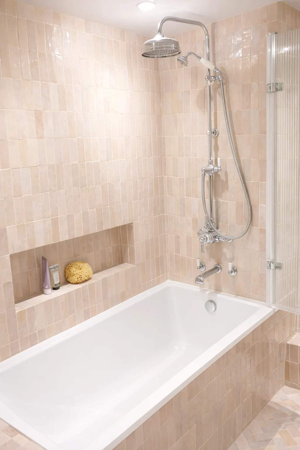 Bath and shower with pale tiled walls