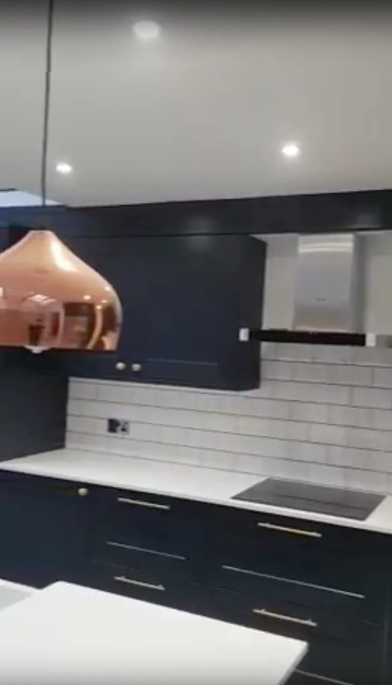 Kitchen cooker wall with dark cupboards and a copper-coloured pendant