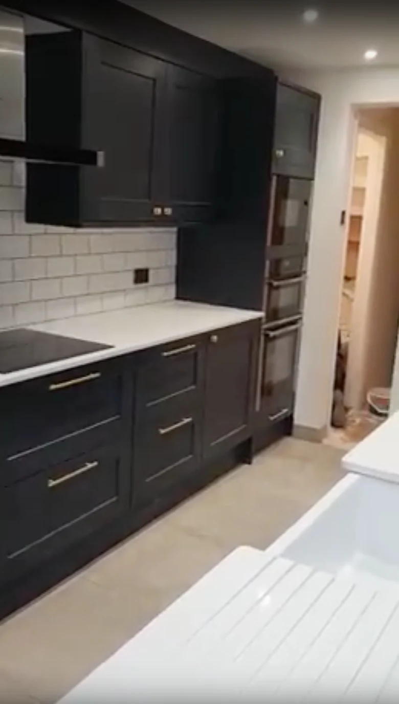 Dark kitchen cabinets with pale worktops and tiled splashback