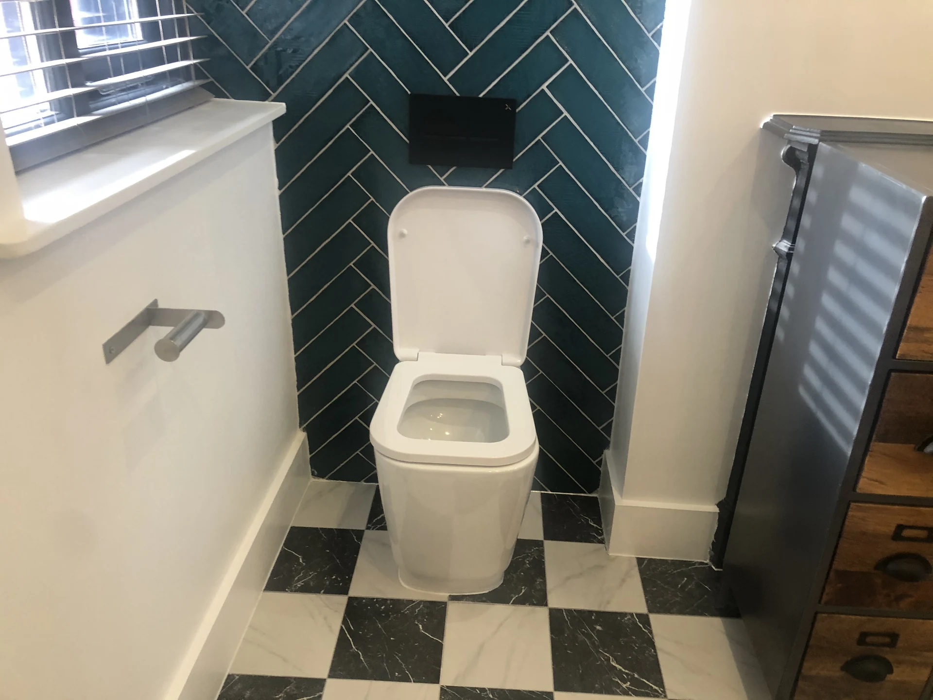 Checkerboard floor tiles and dark wall tiles in the bathroom