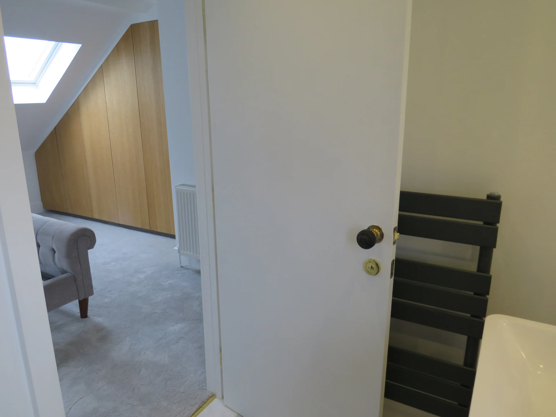 Bathroom doorway opening towards a rooflit upper-floor room