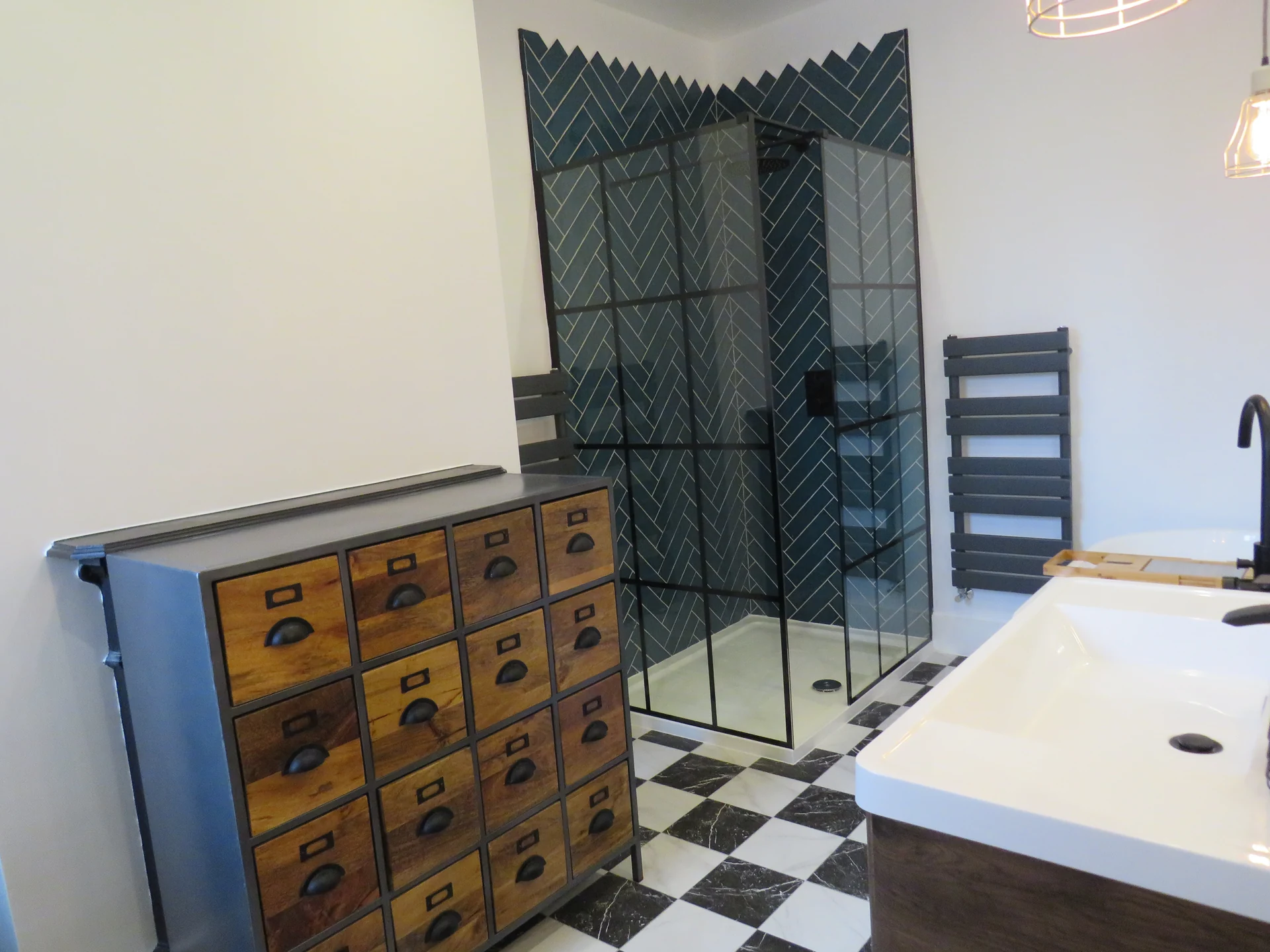 Dark herringbone shower tiles beside a timber vanity