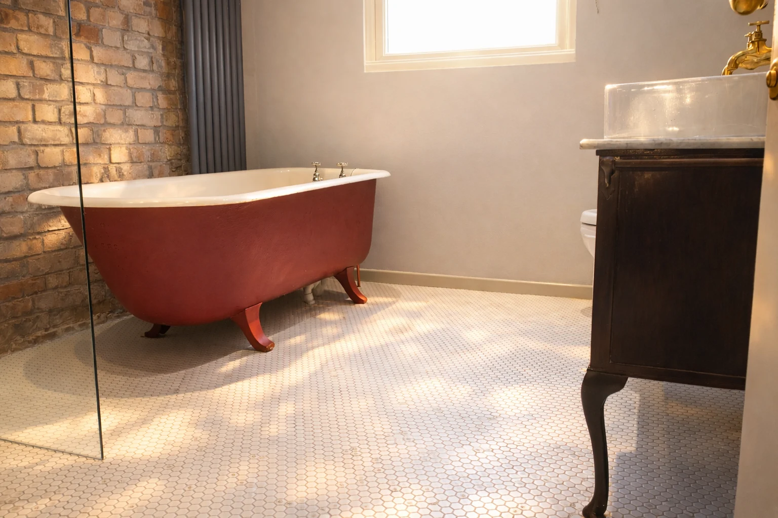Red freestanding bath beside exposed brickwork